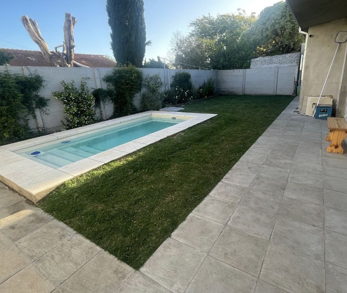 El mismo patio terminado, con césped verde junto a la pileta